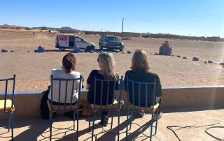 reisgezelschap van 3 mensen op stoelen kijkt uit op de woestijn tijdens een reis op maat